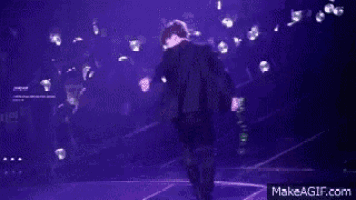a man is kneeling on a stage in front of a crowd of people .
