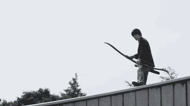 a man is holding a bow and arrow while standing on a wall