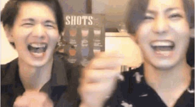 two men are laughing and holding their hands up in the air .