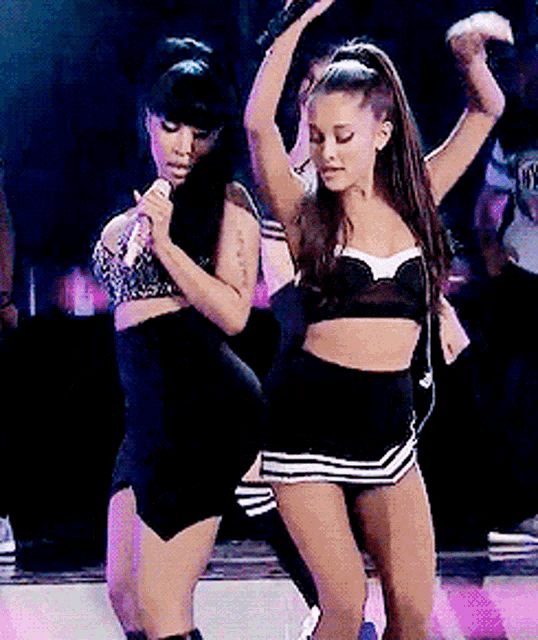 a woman holding a microphone while dancing with another woman
