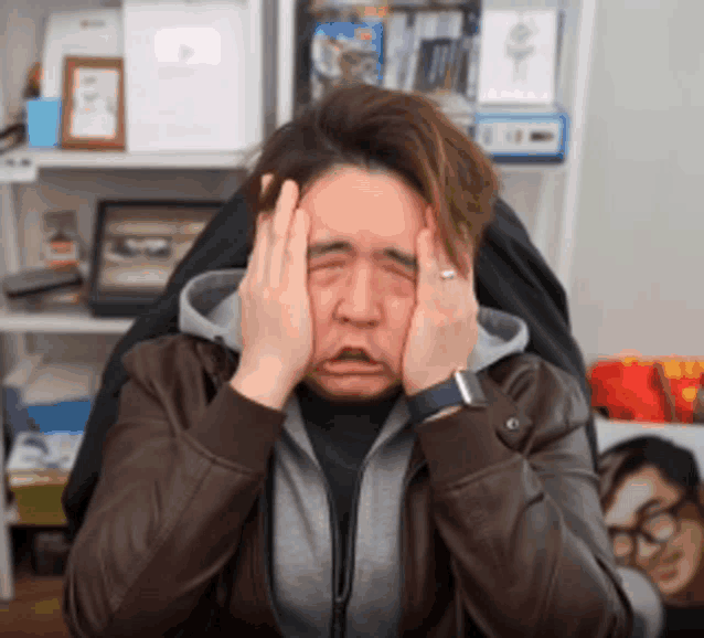a man covering his face with his hands with a ring on his finger