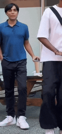 a man in a blue polo shirt stands next to another man in a white shirt