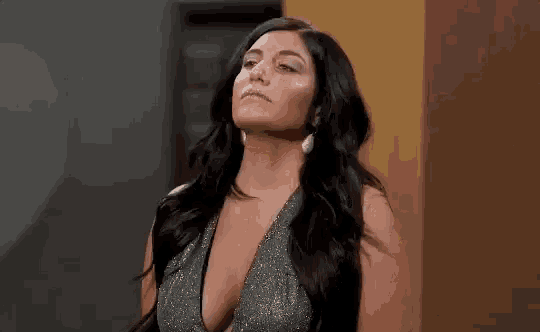 a woman in a plunging neckline dress is standing in front of a wall .