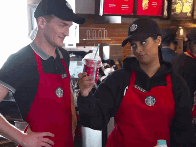 a man and a woman wearing red starbucks aprons stand next to each other