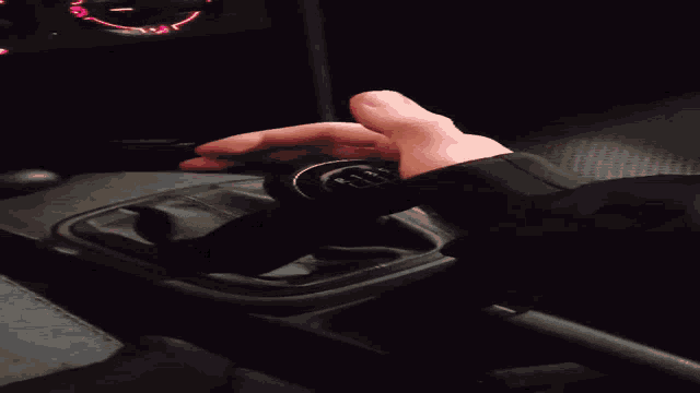 a person 's hand is reaching into a car 's shifter