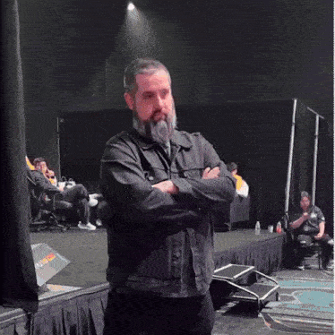 a man with a beard is standing with his arms crossed