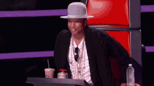 a man wearing a white hat is sitting at a table with a drink and a bottle of water