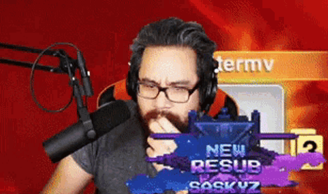 a man wearing glasses and headphones is sitting in front of a microphone and a sign that says new resub saskyz