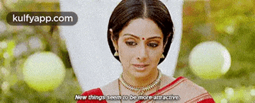 a woman is wearing a red and white saree and a necklace and says `` new things seem to be more attractive ''