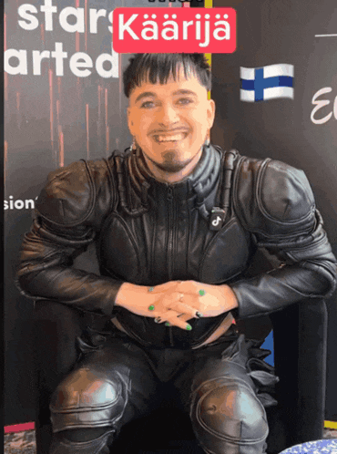 a man in a black leather suit is smiling in front of a sign that says star arted