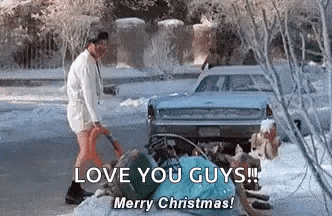 a man is standing next to a car in the snow holding a shovel .