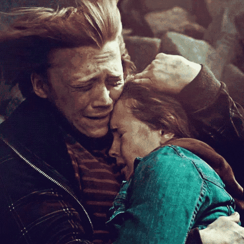 a man and a woman are hugging each other and the woman is crying