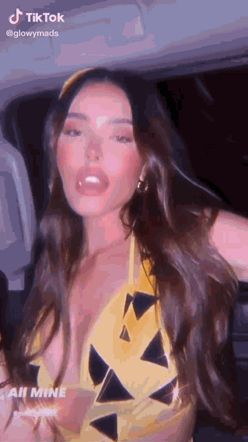 a woman in a yellow bikini is sitting in a car with her mouth open .