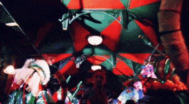 a group of people are standing under a red and green tent