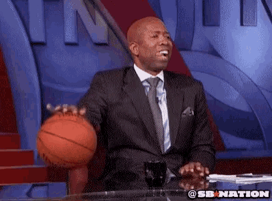 a man in a suit and tie is holding a basketball in front of a screen that says sb nation