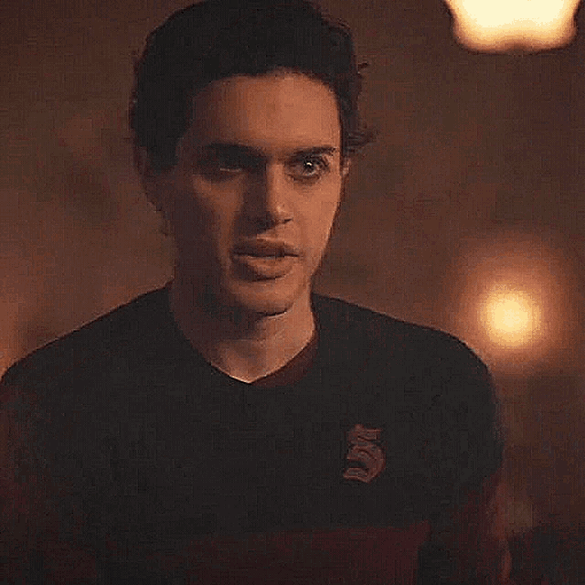 a young man in a black and red sweater is holding a piece of paper .