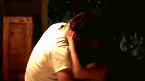 a man is kneeling down with his head in his hands .