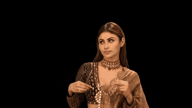 a woman in a gold dress is pointing at herself