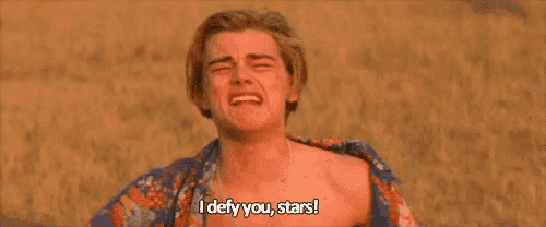 a man without a shirt is sitting in a field with his mouth open and saying `` i defy you , stars '' .