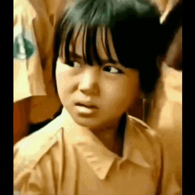 a young girl in a school uniform is making a funny face in a classroom .