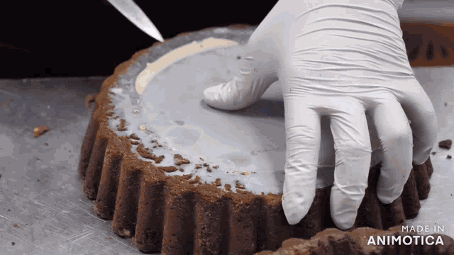 a person wearing white gloves is making a cake with the words made in animotica below it