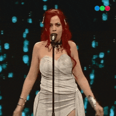a woman with red hair singing into a microphone on a stage