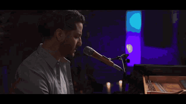 a man with a beard is singing into a microphone with his eyes closed