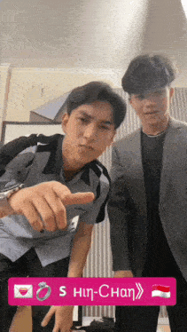 two young men standing next to each other with a pink sticker that says s hin-chan