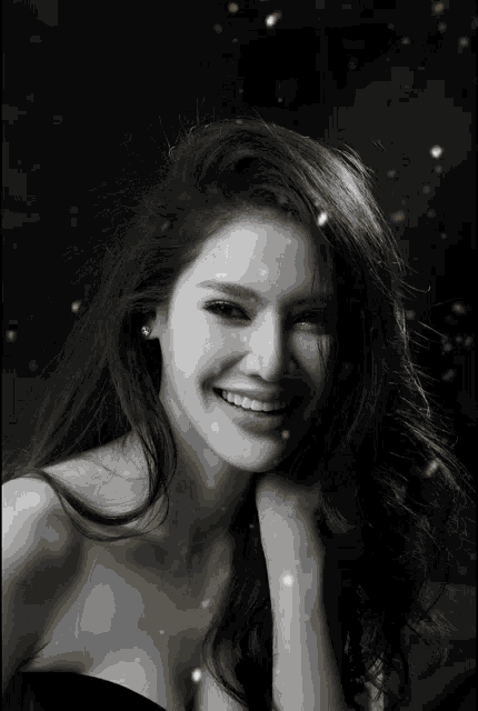 a black and white photo of a woman smiling with gold sparkles coming out of her hair