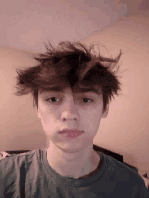 a young man with a messy hair style looks at the camera