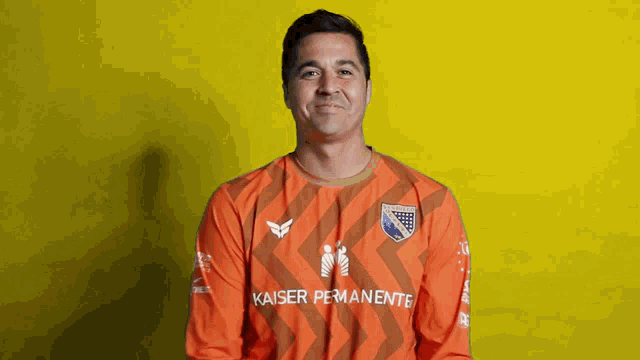 a man wearing an orange kaiser permanente jersey smiles for the camera