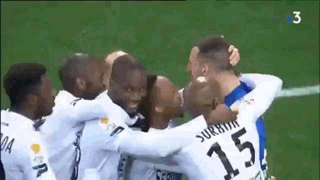 a group of soccer players are hugging each other on a field with the number 15 on their jersey