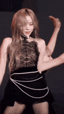 a woman in a black dress with a pearl belt is dancing on stage .