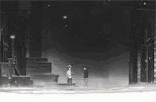 a black and white photo of two people standing next to each other on a snowy street .