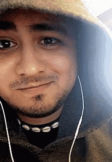 a close up of a man wearing a hoodie and earbuds