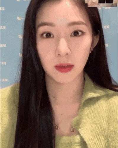a woman with long hair is wearing a green sweater and a necklace