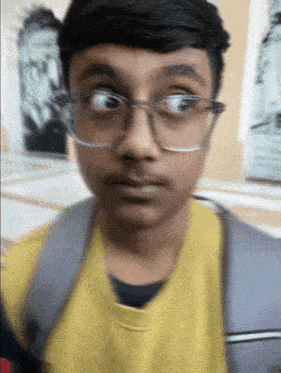 a young boy wearing glasses and a yellow shirt looks at the camera