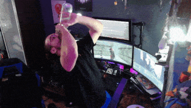 a man is drinking from a glass in front of a computer monitor