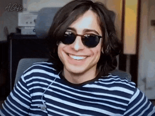 a young man wearing a striped shirt and sunglasses is smiling .