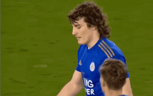 a soccer player in a blue shirt is standing on a field .