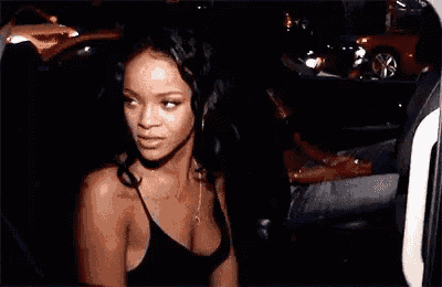 a woman in a black tank top is sitting in a car .