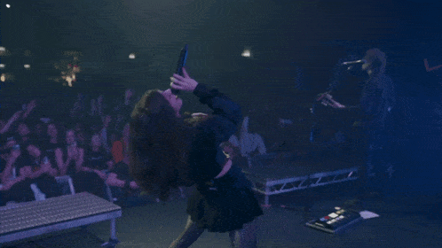 a woman laying on her back on a stage with a microphone in her hand