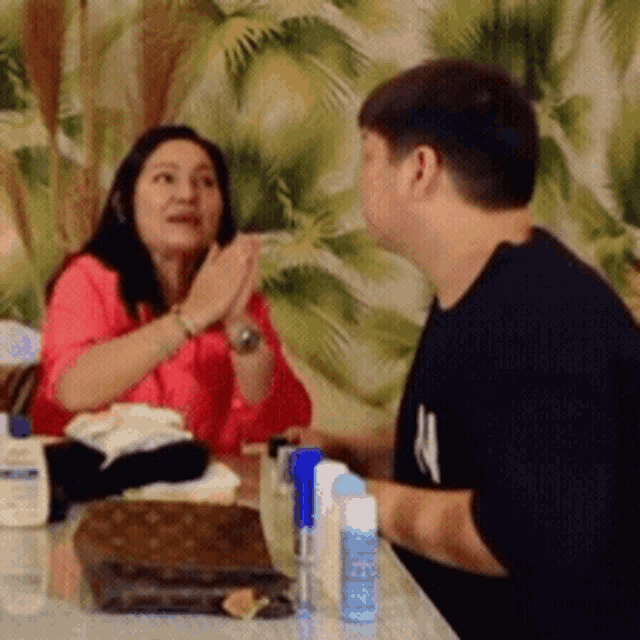 a man and a woman are sitting at a table with a spray bottle that says wipes