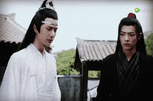 two men are standing next to each other and one of them is wearing a feathered headpiece