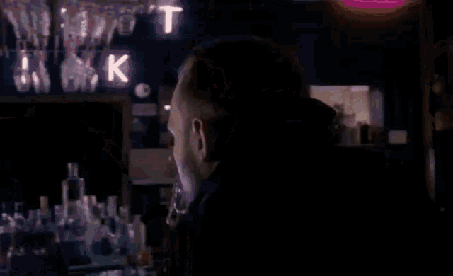 a blurry picture of a man drinking from a bottle in a dark room