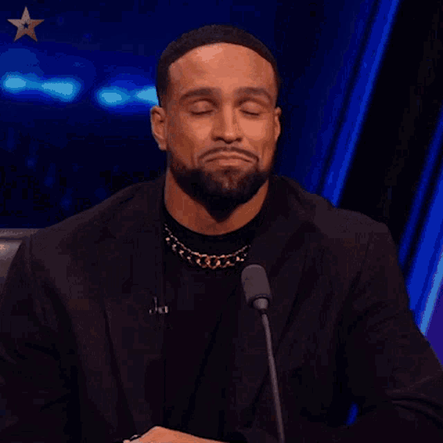 a man with a beard is sitting in front of a microphone with his eyes closed and the word brilliant above him