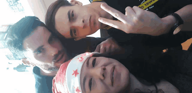 two men and a woman pose for a picture with one wearing a bandana with stars