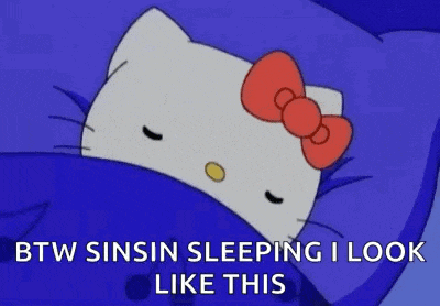 hello kitty is sleeping in a blue bed with a red bow on her head .