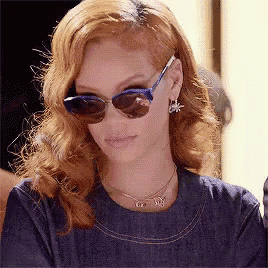 a woman wearing sunglasses and a necklace is looking at the camera .