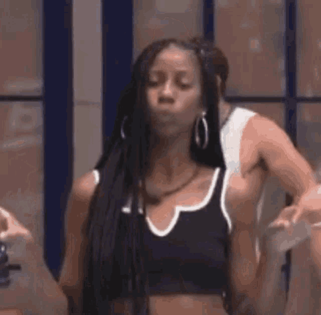 a woman with long braids is standing next to a man in a black tank top .